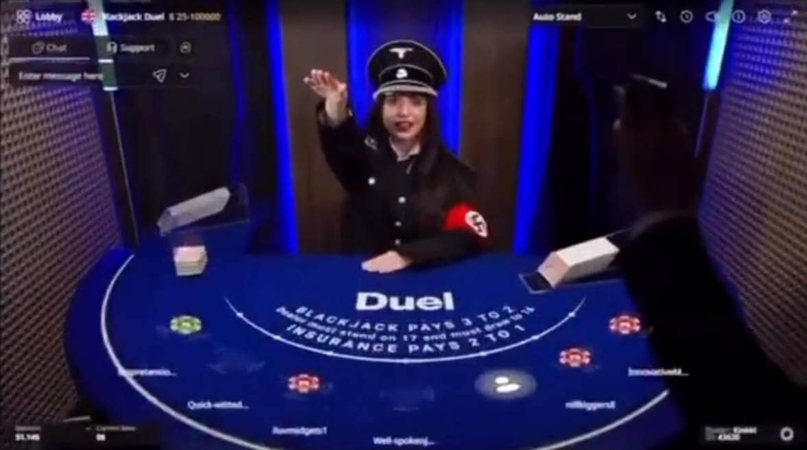 Duel.com live blackjack dealer wearing a Nazi SS-style uniform and armband while performing a salute at the table